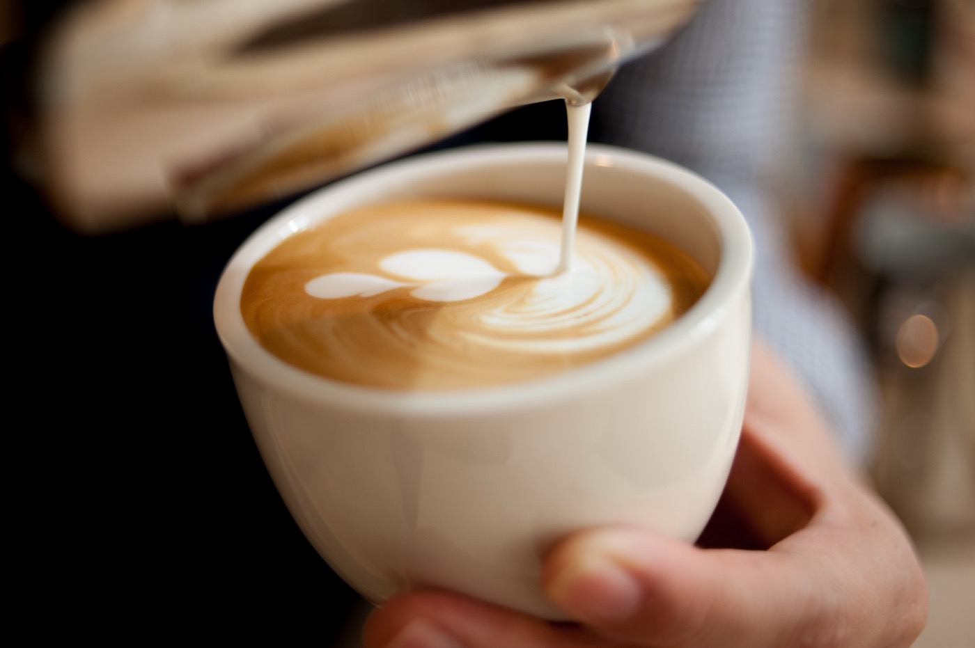 Milk being poured into a latte, making a pattern in the crema